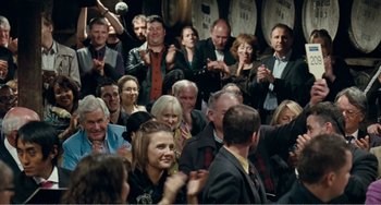Movie still from “The Angels' Share” (2012), directed by Ken Loach – A group of people standing in front of a barrel; Medium shot, Over the shoulder angle