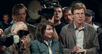 Movie still from “The Angels' Share” (2012), directed by Ken Loach – A group of people gathered around a woman; Medium shot, Over the shoulder angle