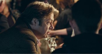 Movie still from “The Angels' Share” (2012), directed by Ken Loach – A man sitting at a table with a glass of wine; Close Up shot, Over the shoulder angle