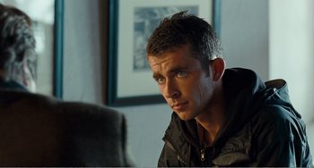 Movie still from “The Angels' Share” (2012), directed by Ken Loach – A man sitting in front of a chair in a room; Close Up shot, Over the shoulder angle