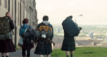 Movie still from “The Angels' Share” (2012), directed by Ken Loach – A group of people in kilts are standing on a hill; Wide shot, Low angle