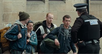 Movie still from “The Angels' Share” (2012), directed by Ken Loach – A group of people standing next to each other near a wall; Medium shot, Over the shoulder angle