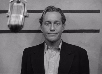 Black and white photograph of a man in front of a microphone