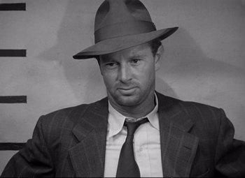 Movie still from “The Asphalt Jungle” (1950), directed by John Huston – Black and white photograph of a man wearing a suit and hat; Close Up shot, Low angle