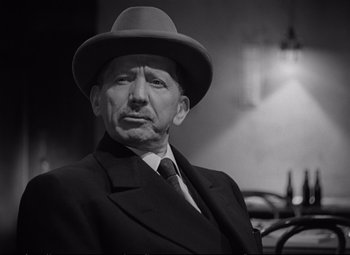 Movie still from “The Asphalt Jungle” (1950), directed by John Huston – An older man wearing a suit and a hat; Close Up shot, Low angle