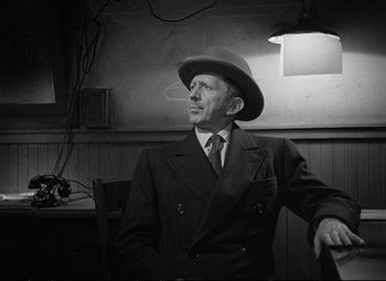 Movie still from “The Asphalt Jungle” (1950), directed by John Huston – An older man wearing a suit and a hat; Medium shot, Low angle