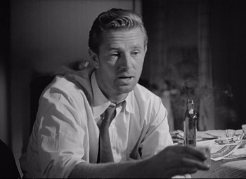 Movie still from “The Asphalt Jungle” (1950), directed by John Huston – A black and white photo of a man holding a bottle; Close Up shot, Over the shoulder angle
