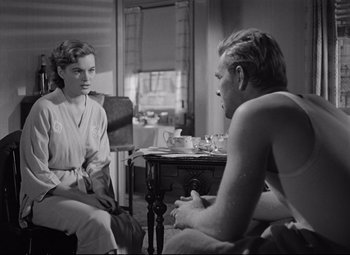 Movie still from “The Asphalt Jungle” (1950), directed by John Huston – A man and a woman sitting at a table talking to each other; Medium shot, Over the shoulder angle