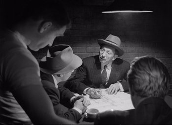 Movie still from “The Asphalt Jungle” (1950), directed by John Huston – A group of men sitting around a table; Medium shot, Over the shoulder angle