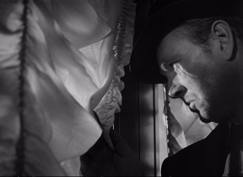 Movie still from “The Asphalt Jungle” (1950), directed by John Huston – A black and white photo of a man looking out a window; Close Up shot, Low angle