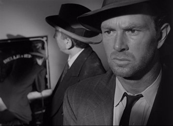 Movie still from “The Asphalt Jungle” (1950), directed by John Huston – A man in a suit and a hat standing next to another man in a suit; Close Up shot, Over the shoulder angle