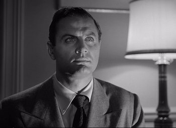 Movie still from “The Asphalt Jungle” (1950), directed by John Huston – Black and white photograph of a man wearing a suit and tie; Close Up shot, Low angle