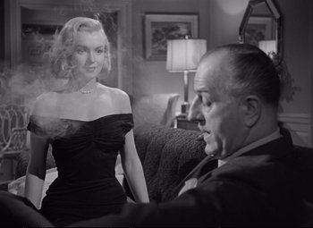 Movie still from “The Asphalt Jungle” (1950), directed by John Huston – A man and a woman sitting on a couch in a living room; Medium shot, Over the shoulder angle