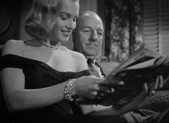 Movie still from “The Asphalt Jungle” (1950), directed by John Huston – An old photo of a man and a woman looking at papers; Close Up shot, Low angle