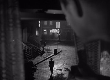 Movie still from “The Asphalt Jungle” (1950), directed by John Huston – A man is standing in the middle of a street; Wide shot, Over the shoulder angle