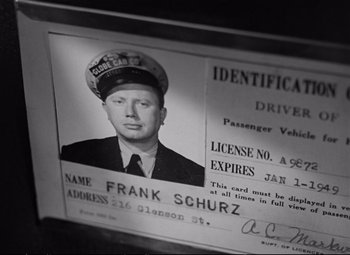 Movie still from “The Asphalt Jungle” (1950), directed by John Huston – An old photo of a man in a hat and uniform; Close Up shot, High angle