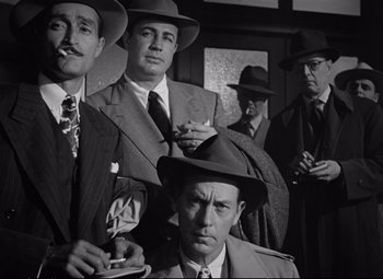 Movie still from “The Asphalt Jungle” (1950), directed by John Huston – A black and white photo of a group of men smoking; Medium shot, Low angle