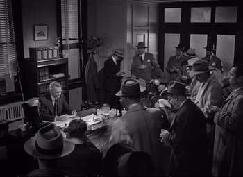 Movie still from “The Asphalt Jungle” (1950), directed by John Huston – A black and white photo of a group of men sitting around a table; Wide shot, High angle