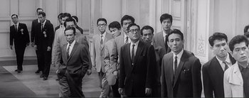 Movie still from “The Bad Sleep Well” (1960), directed by Akira Kurosawa – Black and white photograph of a group of men in suits and ties; Medium shot, Low angle