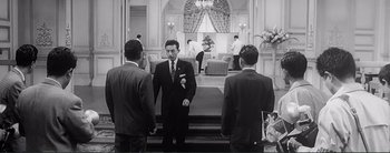 Movie still from “The Bad Sleep Well” (1960), directed by Akira Kurosawa – A man in a suit standing next to two other men in suits; Wide shot, Low angle