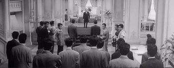 Movie still from “The Bad Sleep Well” (1960), directed by Akira Kurosawa – A group of people standing in front of a stage; Extreme Wide shot, High angle