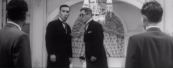 Movie still from “The Bad Sleep Well” (1960), directed by Akira Kurosawa – Two men standing next to each other in front of a mirror; Medium shot, Low angle