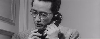 Movie still from “The Bad Sleep Well” (1960), directed by Akira Kurosawa – A man holding a phone up to his ear; Close Up shot, Low angle