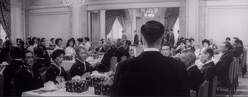 Movie still from “The Bad Sleep Well” (1960), directed by Akira Kurosawa – A group of people sitting around a table; Medium shot, Over the shoulder angle