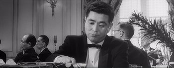 Movie still from “The Bad Sleep Well” (1960), directed by Akira Kurosawa – A black and white photo of a man in a tuxedo; Close Up shot, Over the shoulder angle