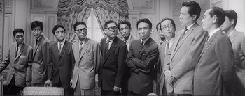 Movie still from “The Bad Sleep Well” (1960), directed by Akira Kurosawa – A black and white photo of a group of men in suits; Medium shot, Low angle