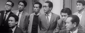 Movie still from “The Bad Sleep Well” (1960), directed by Akira Kurosawa – A black - and - white photo of two men standing next to each other; Medium shot, Low angle