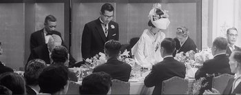 Movie still from “The Bad Sleep Well” (1960), directed by Akira Kurosawa – A man and a woman standing in front of a table; Medium shot, Over the shoulder angle