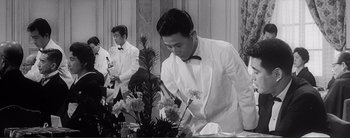 Movie still from “The Bad Sleep Well” (1960), directed by Akira Kurosawa – A man in a white suit and a man in a black bow tie; Medium shot, Low angle