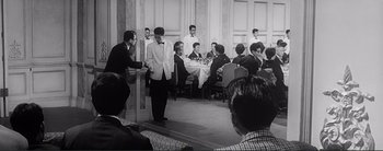 Movie still from “The Bad Sleep Well” (1960), directed by Akira Kurosawa – A black and white photo of a group of people in a room; Wide shot, Over the shoulder angle