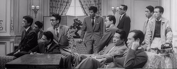 Movie still from “The Bad Sleep Well” (1960), directed by Akira Kurosawa – A black and white photo of a group of men sitting on a couch; Medium shot, Low angle