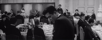 Movie still from “The Bad Sleep Well” (1960), directed by Akira Kurosawa – A black and white photo of a man at a table; Medium shot, Over the shoulder angle
