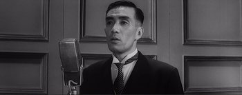 Movie still from “The Bad Sleep Well” (1960), directed by Akira Kurosawa – Black and white photograph of a man wearing a suit and tie; Close Up shot, Low angle