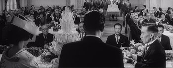 Movie still from “The Bad Sleep Well” (1960), directed by Akira Kurosawa – A group of men standing around a table; Medium shot, Over the shoulder angle