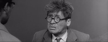 Movie still from “The Bad Sleep Well” (1960), directed by Akira Kurosawa – An old man with glasses is wearing a suit and a wig; Close Up shot, Low angle