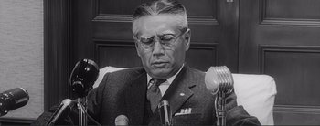 Movie still from “The Bad Sleep Well” (1960), directed by Akira Kurosawa – An old photo of a man in a suit and tie; Close Up shot, Low angle