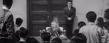 Movie still from “The Bad Sleep Well” (1960), directed by Akira Kurosawa – An old photo of a man smoking a cigarette in a room; Medium shot, Low angle