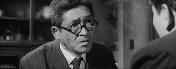 Movie still from “The Bad Sleep Well” (1960), directed by Akira Kurosawa – An older man wearing a suit and glasses; Close Up shot, Over the shoulder angle