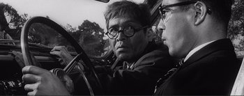 Movie still from “The Bad Sleep Well” (1960), directed by Akira Kurosawa – A black and white photo of a man driving a car; Close Up shot, Over the shoulder angle
