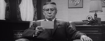 Movie still from “The Bad Sleep Well” (1960), directed by Akira Kurosawa – An older man holding a piece of paper in his hand; Medium shot, Low angle