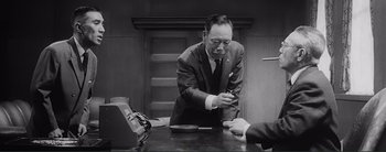 Movie still from “The Bad Sleep Well” (1960), directed by Akira Kurosawa – An older man in a suit and tie at a desk; Medium shot, Low angle