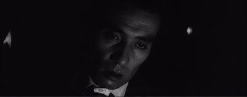 Movie still from “The Bad Sleep Well” (1960), directed by Akira Kurosawa – A black and white photo of a man in a suit and tie; Close Up shot, High angle