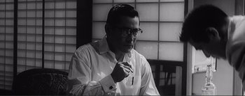 Movie still from “The Bad Sleep Well” (1960), directed by Akira Kurosawa – An older man wearing a white shirt is smoking a cigarette; Close Up shot, Low angle
