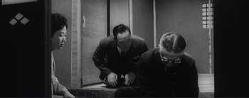 Movie still from “The Bad Sleep Well” (1960), directed by Akira Kurosawa – A man in a suit kneeling on the ground; Medium shot, Low angle