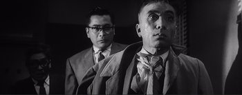 Movie still from “The Bad Sleep Well” (1960), directed by Akira Kurosawa – Two men in suits and ties looking at the camera; Medium shot, Low angle