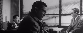 Movie still from “The Bad Sleep Well” (1960), directed by Akira Kurosawa – A black and white photo of a man looking out of a window; Close Up shot, Low angle